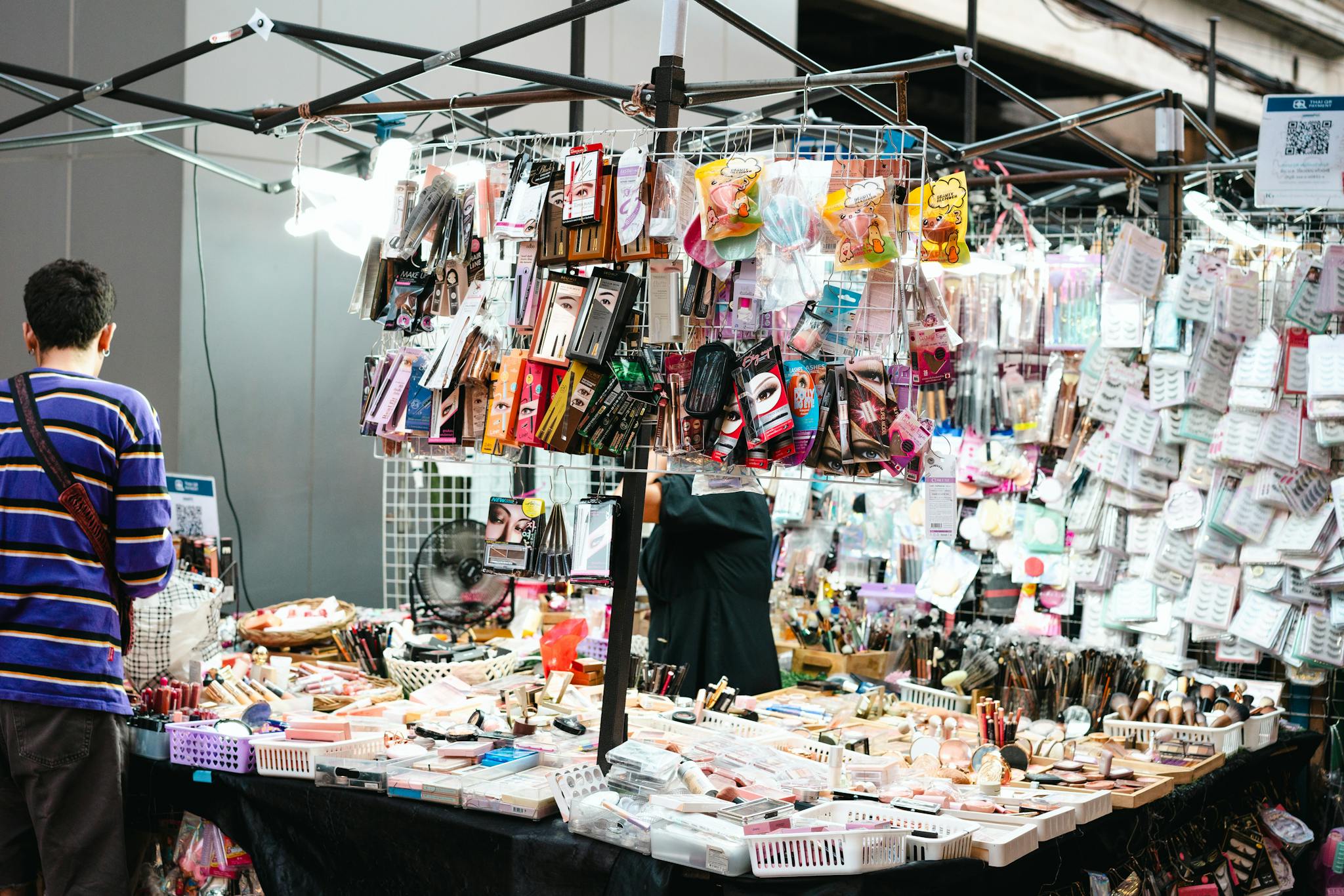 A vibrant market stall displaying a variety of cosmetics and makeup items for sale.